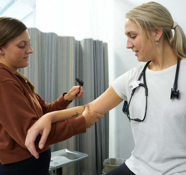 Two female students practicing reflex testing