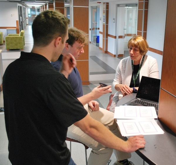 Students in the hall talking with their professor.